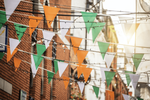 Orange, green and white triangular flags hang between buildings.