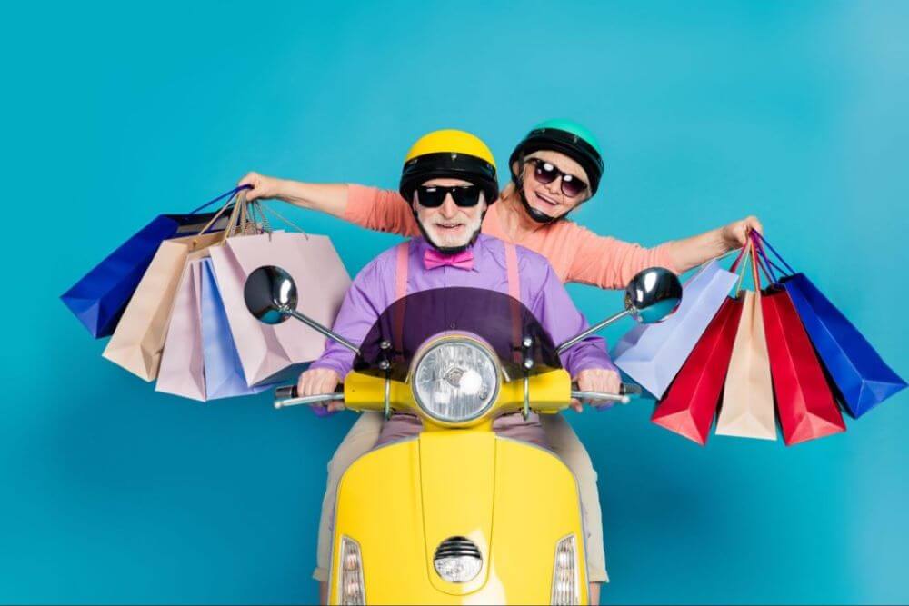 casal de idosos em uma motocicleta com várias sacolas representando compras