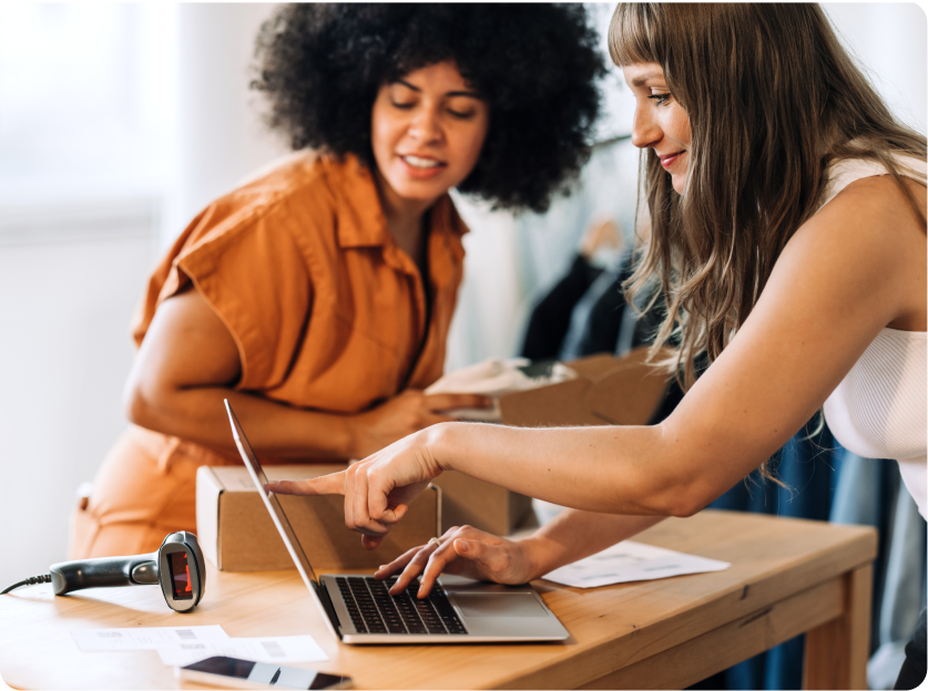 Dos mujeres multirraciales mirando una computadora portátil. Una de las mujeres está señalando algo en el monitor.